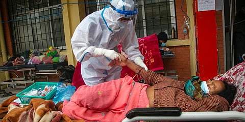 Nepalese paramedics treat a COVID-19 patient outside an emergency ward of a government run hospital in Kathmandu. (File Photo | AP)