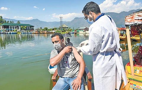 A medic administers Covid-19 vaccine to a man, during a special vaccination drive for boatmen, at the banks of Dal Lake in Srinagar on Thursday | PTI