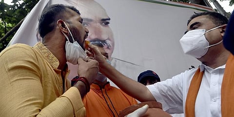 BJP leader Suvendu Adhikari with cricketer Ashok Dinda during Paschim Banga Dibos at state party office in Kolkata on Sunday. (Photo | PTI)