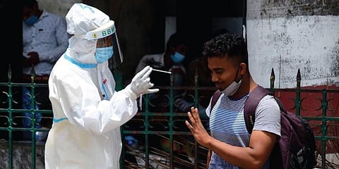 A health worker collects swab samples of a passenger at Krantivira Sangolli Rayanna Railway Station in Bengaluru on Sunday. (Photo | Shriram BN, EPS)