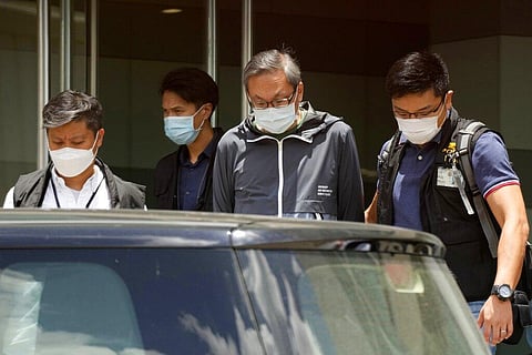 In this Thursday, June 17, 2021, file photo, police officers escort Cheung Kim-hung, center, CEO and Executive Director of Next Digital Ltd at Apple Daily headquarters in Hong Kong. (Photo | AP)