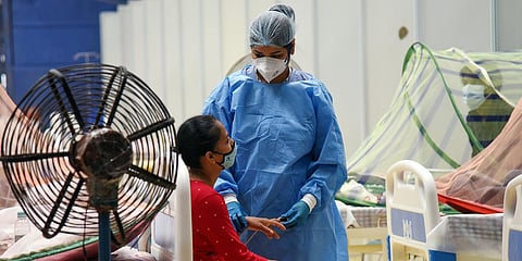 An healthcare worker in PPE kit treats COVID-19 patient at CWG COVID care center, in New Delhi. (Photo| ANI)