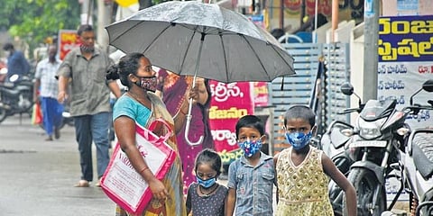 A mother protects her children from drizzle in Vijayawada on Saturday. (Photo | Express)