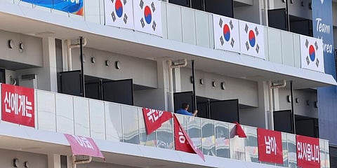 Banners with the words 'I still have the support of 50 million Korean people', are removed from balconies at the Olympic athletes' village in Tokyo. (Photo | AP)