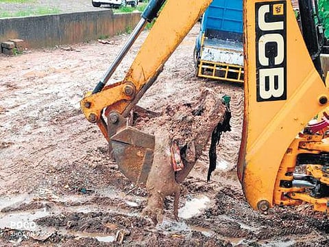 An earth mover recovering carcasses of dogs from the dumping yard