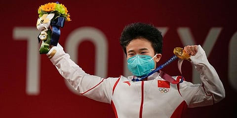 Hou Zhihui of China celebrates on the podium after winning the gold medal in the women's 49kg weightlifting event, at the 2020 Summer Olympics in Tokyo, Japan. (Photo | AP)