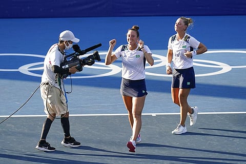Luisa Stefani, center, and Laura Pigossi, of Brazil, celebrate after defeating Veronika Kudermetova and Elena Vesnina, of the Russian Olympic Committee. (Photo | AP)