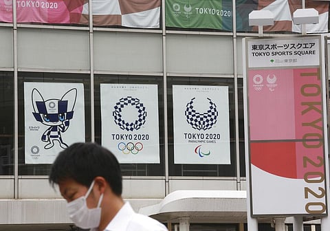 A man wearing a face mask to protect against the spread of the coronavirus walks by posters to promote the Tokyo Olympic Games in Tokyo. (Photo | AP)