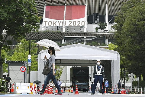 People wearing face masks walk past the National Stadium in Tokyo, Thursday, July 8, 2021. (Photo | AP)