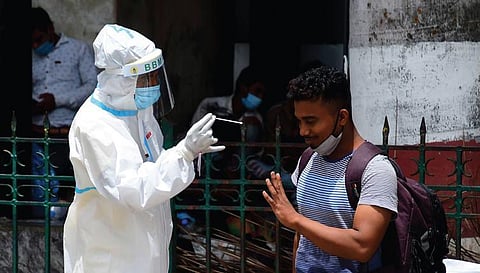 A health worker collects swab samples of a passenger at Krantivira Sangolli Rayanna Railway Station in Bengaluru. (Photo | Shriram BN, EPS)