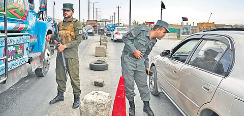 Afghan policemen stand guard at a checkpoint along a road in Kabul on Saturday | AFP