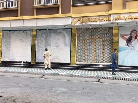 A photo of two men whitewashing such posters in the city has gone viral on Twitter. (Photo | Twitter)