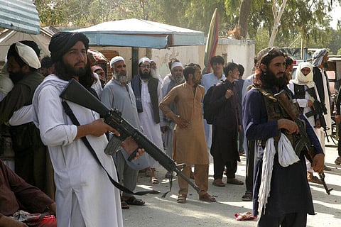 Taliban fighters stand guard on their side while people wait to cross at a border crossing point between Pakistan and Afghanistan, in Torkham (Photo | AP)