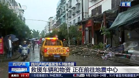 In this image made from video run by China's CCTV, people walk by damaged shophouses following an earthquake in Luxian County. (Photo | AP)