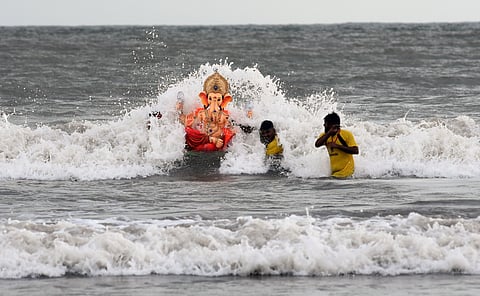 Volunteers carry a Ganesh idol to immerse it in the Arabian sea on the 10th day of ongoing Ganesh Utsav, at Juhu Beach, in Mumbai on Sunday.