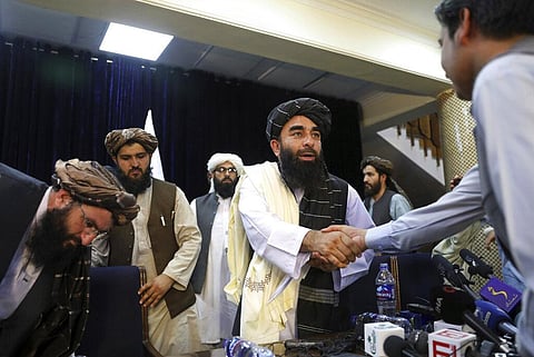 In this Aug. 17, 2021, file photo, Taliban spokesman Zabihullah Mujahid, shakes hands with a journalist after his first news conference, in Kabul, Afghanistan. (Photo | AP)