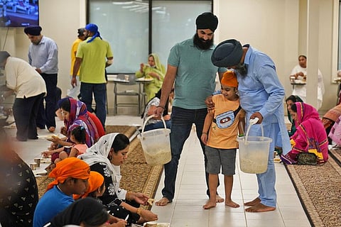 Raghuvinder Singh, right, greets a child while helping to serve food after a Sikh worship service at a gurdwara in Glen Rock, N.J., Sunday, Aug. 15, 2021. (Photo | AP)