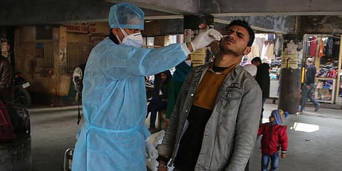 A health worker collects a swab sample from a passenger to test for COVID-19 at a bus station. (Photo | AP)