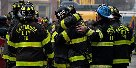 Firefighters embrace each other after a deceased firefighter was pulled out of a building collapse while battling a two-alarm fire in a vacant row home in Baltimore. (Photo | AP)
