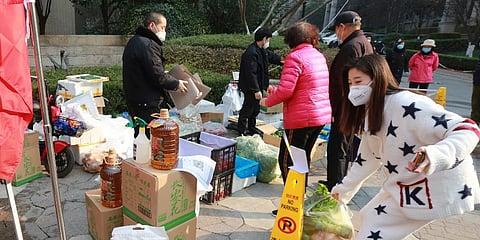 Residents shop for food at a temporary food store set up to serve residents outside a residential block after the suspension of delivery services in Xi'an. (Photo | AP)