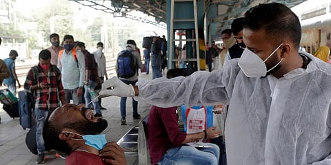 A health worker collects a swab sample from a traveler at a railway station to test for COVID-19 in Mumbai. (Photo | AP)