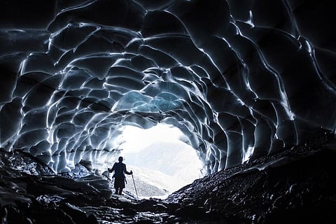 A man stands in a glacier cave at the Sardona glacier, July 27, 2022, in Vaettis, Switzerland. The melting glacier has revealed a cave. (File Photo|AP)