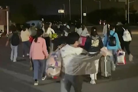 In this photo taken from video footage and released by Hangpai Xingyang, people with suitcases and bags are seen leaving from a Foxconn compound in Zhengzhou in central China's Henan Province (AP)
