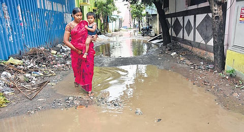 A woman negotiating a waterlogged road on Mangaliamman Kovil Street at Kovilambakkam following a spell of rain | Ashwin prasath