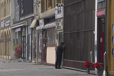 A security guard peers into a store along a stretch of shuttered restaurants in Beijing, Nov. 24, 2022.(Photo | AP)
