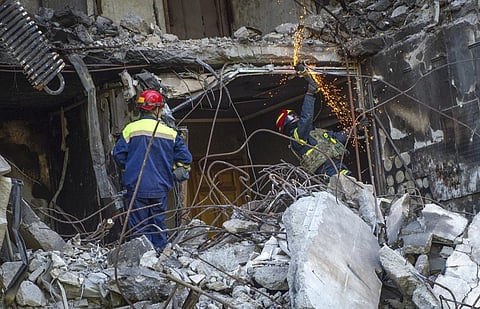 Ukrainian emergency service personnel work outside the damaged building following a shelling. (Photo | AP)