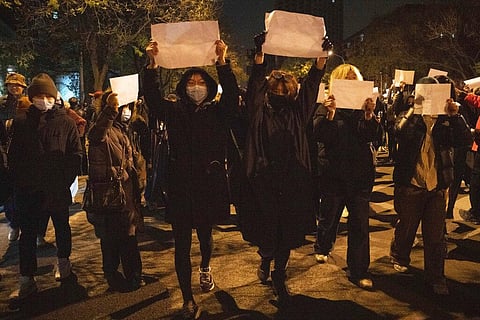 Protesters hold up blank papers and chant slogans as they march in protest in Beijing, Nov. 27, 2022. (File Photo | AP)