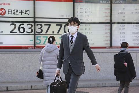 People walk by an electronic stock board of a securities firm in Tokyo, Tuesday, Feb. 22, 2022. (Photo | AP)