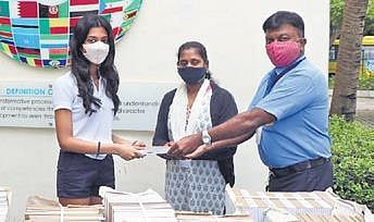 A 17-year-old student Diya (centre) distributes the re-purposed notebooks. (Photo | EPS)