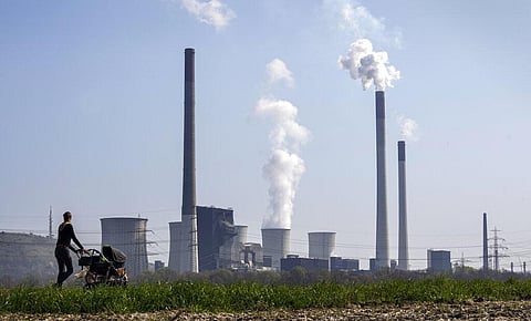 A mother pushes a stroller in front of the Scholven coal fired power station, owned by Uniper, in Gelsenkirchen, Germany. (Photo | AP)