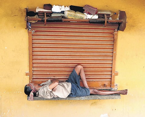 A worker takes a nap outside a closed shop in Bhubaneswar | Express