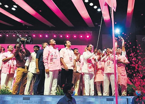 Chief Minister K Chandrasekhar Rao hoists the party flag at the 21st plenary of the TRS at the HICC, while women leaders, right, give a thumbs up on Wednesday