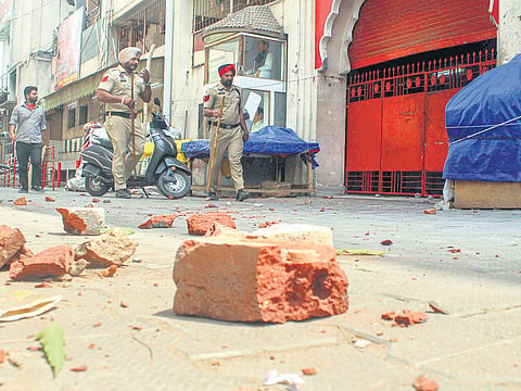 Bricks on the ground as security personnel patrol after a clash between two groups near Kali Mata Mandir in Patiala on Friday