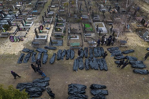 Policemen work on the identification process following the killing of civilians in Bucha, before sending the bodies to the morgue, on the outskirts of Kyiv, Ukraine. (Photo | AP)