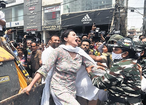 A woman is taken away by security personnel while trying to stop a bulldozer from rolling on during an anti-encroachment drive of the South Delhi Municipal Corporation at Shaheen Bagh area on Monday.