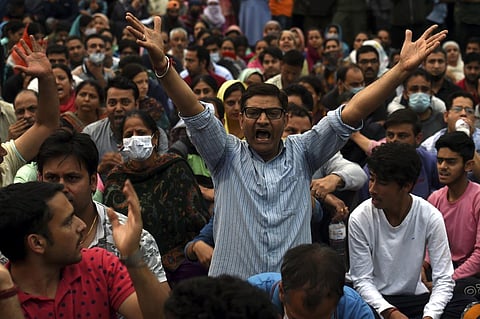 Kashmiri pandits shout slogans while blocking a road during their protest over the killing of Rahul Bhat, who was shot at by militants inside his office and later succumbed to injuries. (Photo | PTI)