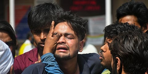 Family members of the missing people who are unsure about their whereabouts react after a massive fire at an office building near the Mundka Metro Station, outside Sanjay Gandhi Memorial Hospital in N