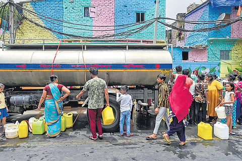 Residents wait in line to collect drinking water from a tanker at Laxmi Bai Nagar| pti
