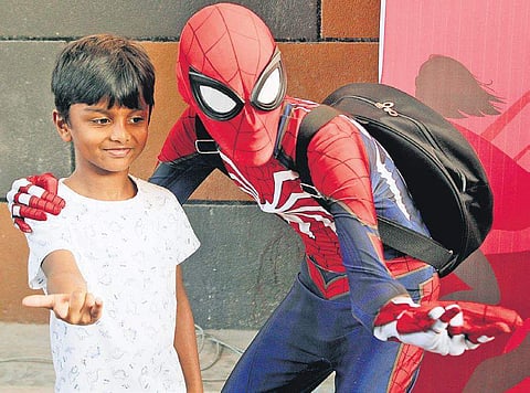 A child poses with a cosplayer dressed as Spiderman. (Photo| EPS)