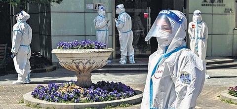 Workers and volunteers look on in a compound where residents are tested for the Covid-19 pandemic in Shanghai. (File Photo | AFP)