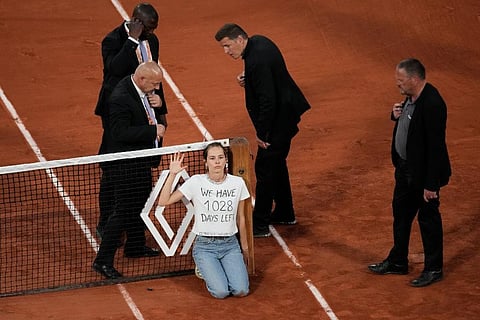 A climate activist tied herself to the net during the semi-final match between Croatia's Marin Cilic and Norway's Casper Ruud at the French Open tennis tournament. (Photo | AP)