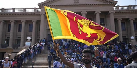 A protester waves a Sri Lankan national flag outside President Gotabaya Rajapaksa's office in Colombo, Sri Lanka, Wednesday, July 13, 2022. (AP/PTI)