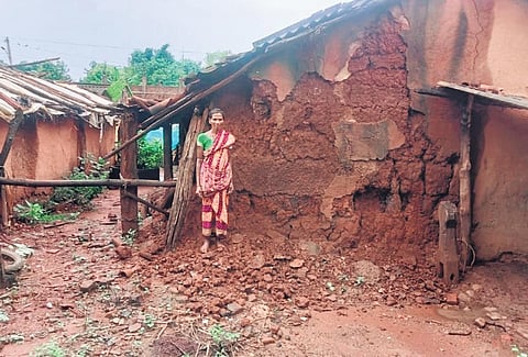 A woman standing in front of her damaged house | Express