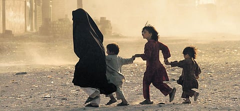 In this file photo, a family runs across a dusty street in Herat. Due to decades of conflict, women and children have been the most vulnerable sections in Afghanistan. UNAMA/Fraidoon Poya