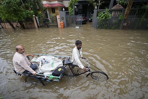 A cycle rickshaw puller transports a man through a water logged road after heavy rain in Ahmedabad. (File | AP)