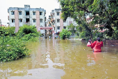 A woman holding essentials walks back to her apartment, wading through floodwater | Express
